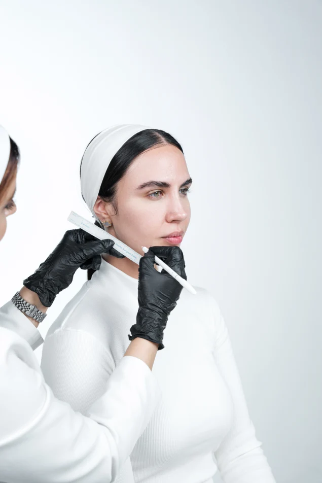 Specialist measuring a patient’s jawline during a facial contouring assessment at Padra Clinic